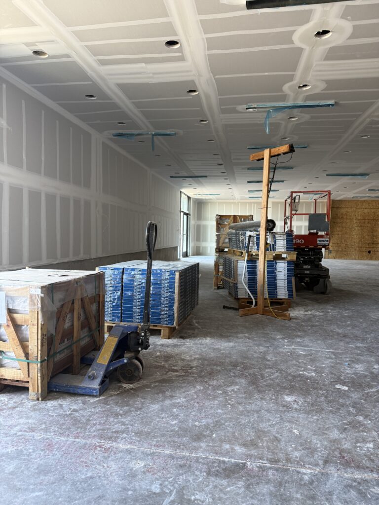 Behind the scenes Instagram photo of a commercial interior under construction, showing drywall installation, stacked materials, and early stage interior design progress.